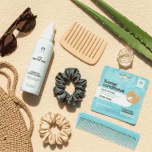 Flat lay of summer hair products including SPF spray, deep conditioner, and scrunchies.
